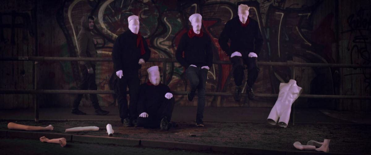 Eine Gruppe von Matrosen, deren Gesichter von einer weißen Stoffmaske bedeckt ist.
